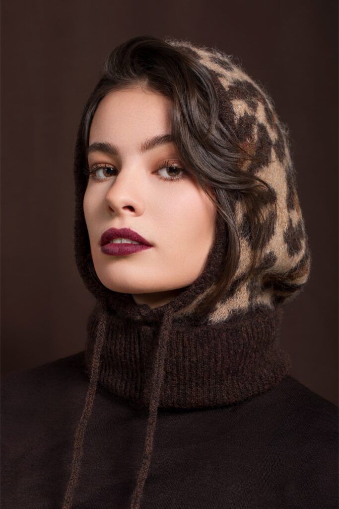 Portrait beauté d’une femme aux cheveux ondulés portant un vêtement sombre sur fond MARRON