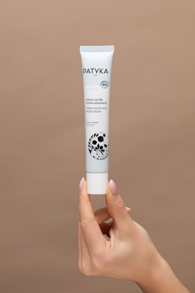 Packshot d’un produit cosmétique Patyka tenu à la main sur fond neutre