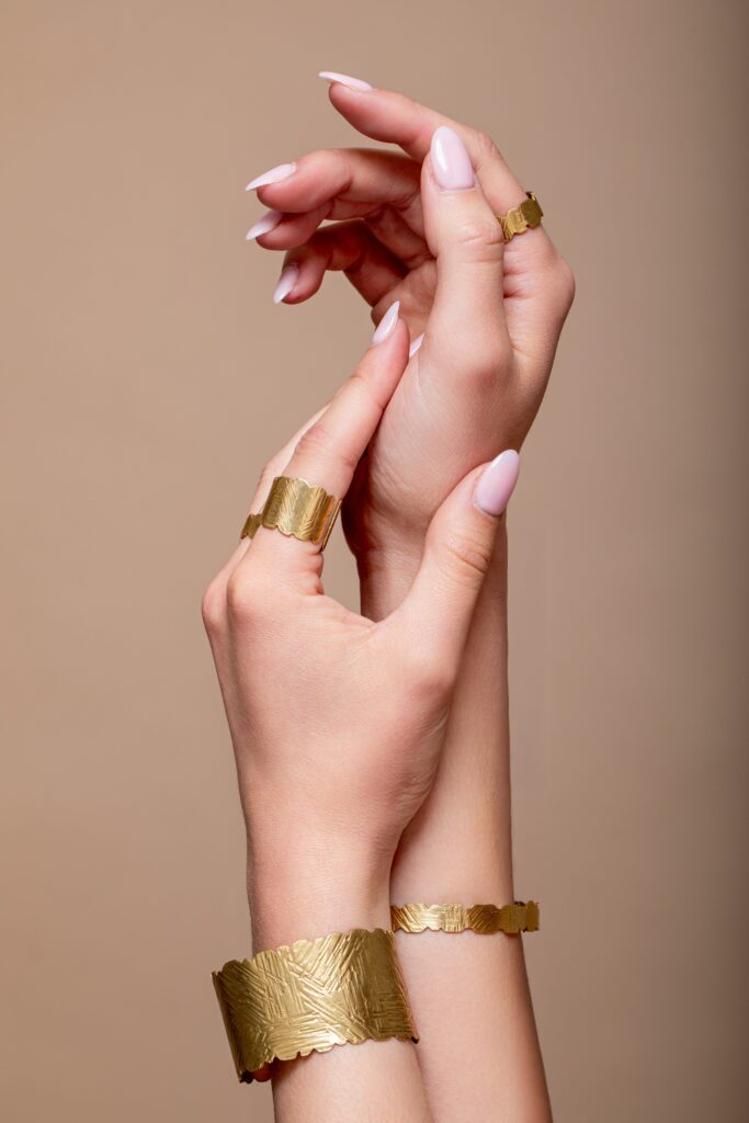 Main féminine portant un bracelet doré, composition minimaliste sur fond beige