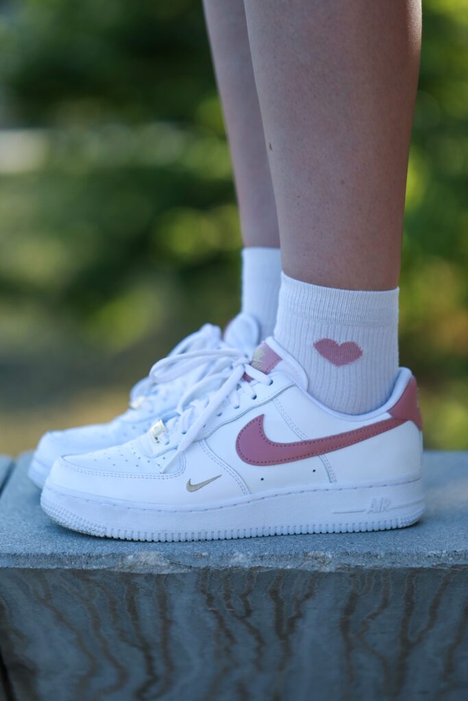 Gros plan sur sneakers Nike blanches avec logo rouge, détail mode streetwear en extérieur