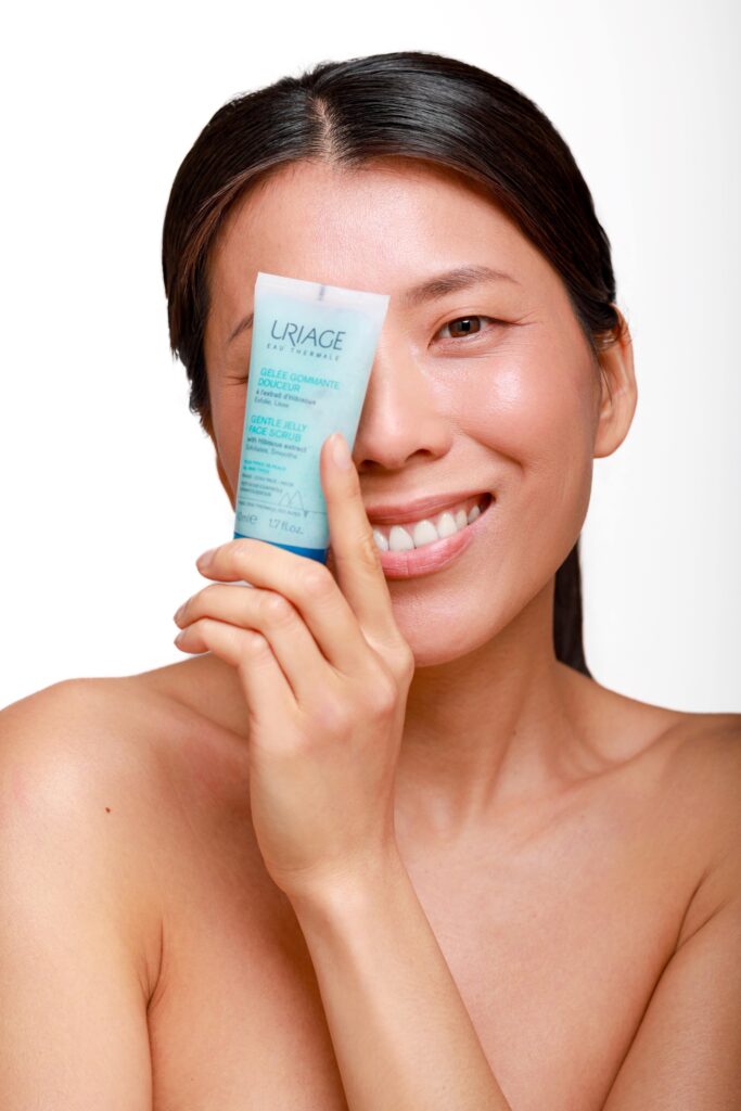 Portrait beauté d’une femme tenant un produit cosmétique Uriage devant son visage