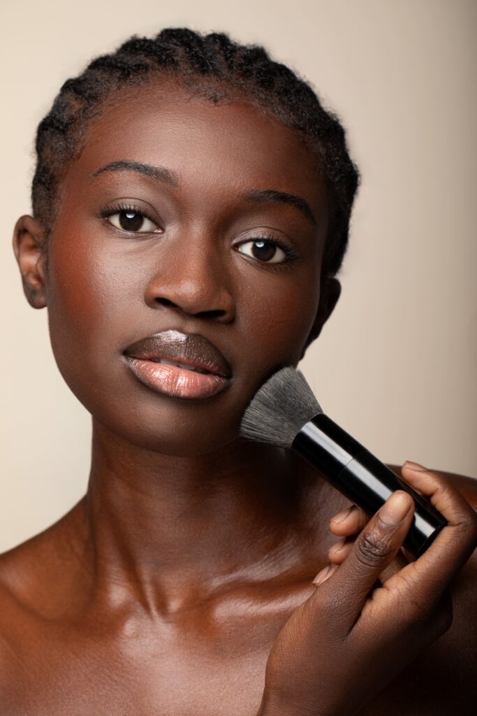 Portrait beauté d’une femme appliquant du maquillage avec un pinceau en studio