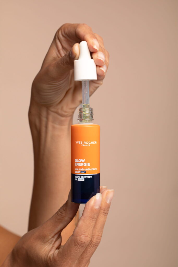 Main tenant un flacon de soin cosmétique avec pipette sur fond neutre