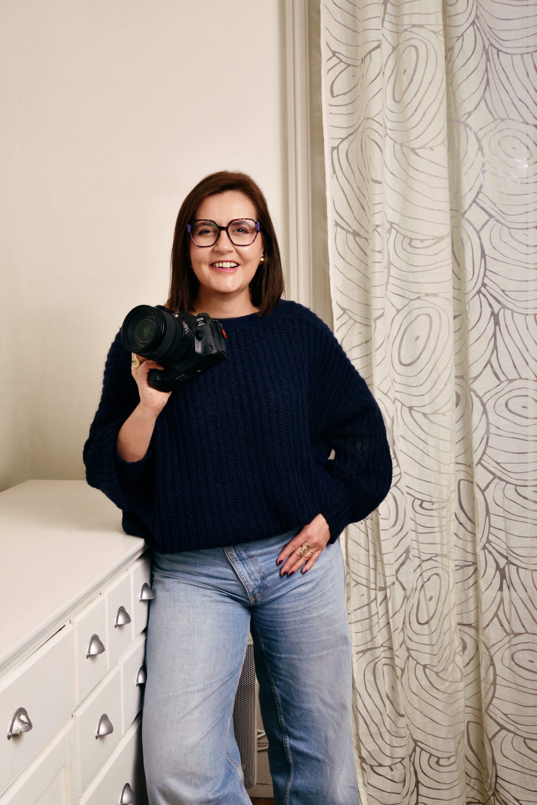 Photographe femme tenant un appareil photo en intérieur, portrait professionnel lumineux