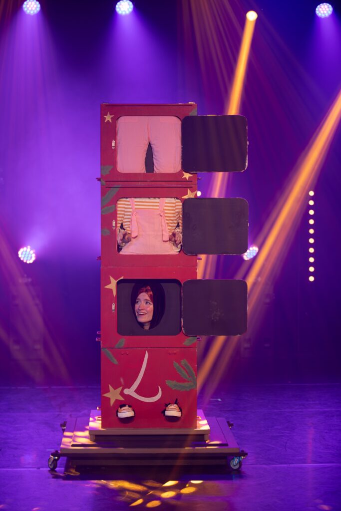 Tour de magie sur scène avec illusionniste dans une boîte compartimentée, éclairage coloré, photographie de spectacle à Lyon