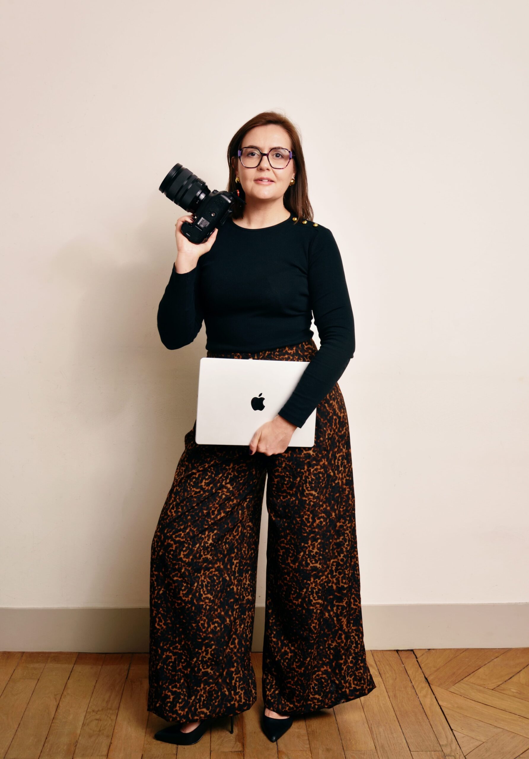 Stéphanie photographe et vidéaste à Lyon tenant un appareil photo et un ordinateur portable en studio