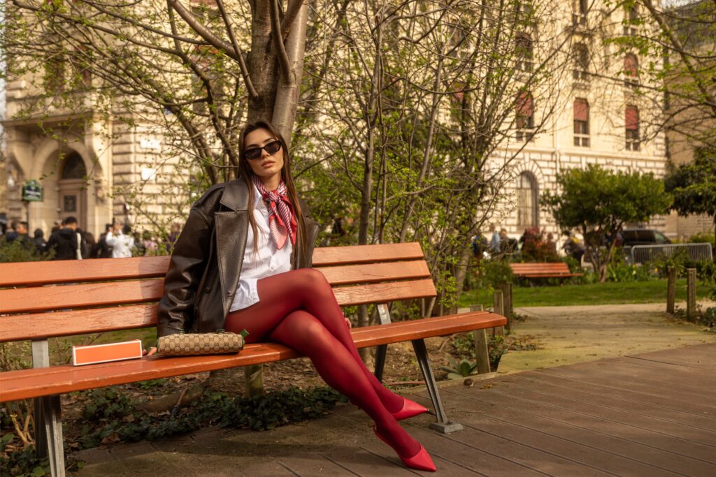 modèle en tenue mode avec collants rouges dans un jardin urbain à Paris